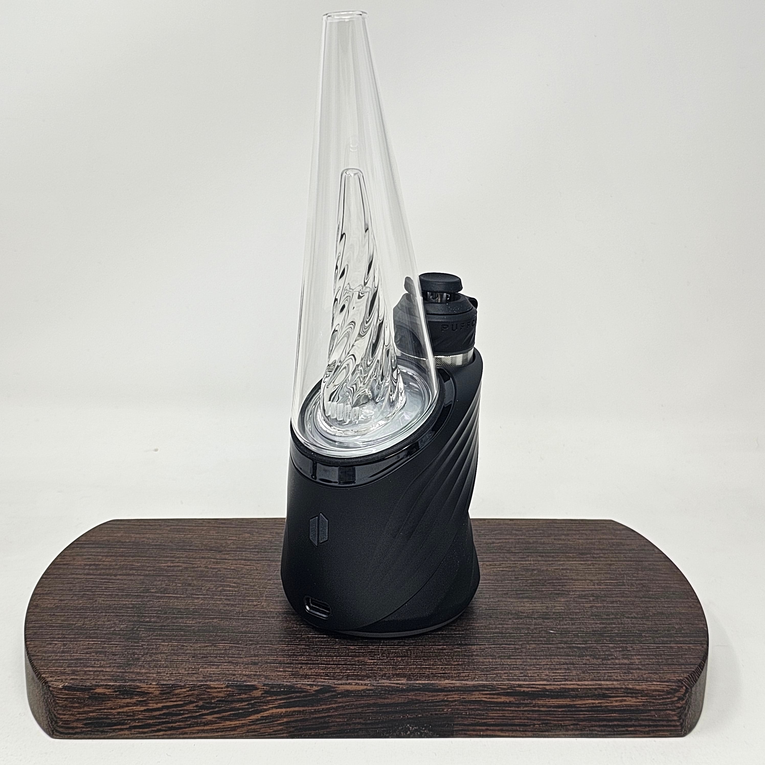 The Peak Pro (2023) is the pinnacle of hash technology. This premium smart rig delivers incredible flavor and unparalleled performance. Unlock the fullest potential of the plant with its single-button interface, deep customization via the Puffco Connect app, and patented 3D Chamber. Featuring the Joystick Cap and laser cut perc slots for improved water filtration. Currently available in Black and Pearl White.